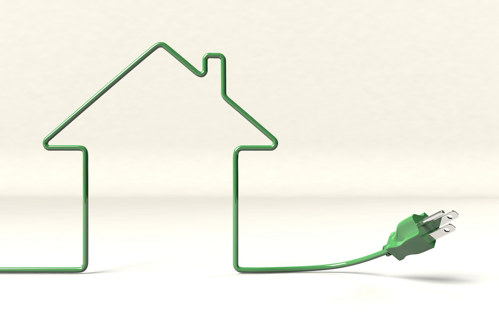 An outline of a house made with a green electrical cord, on white background.